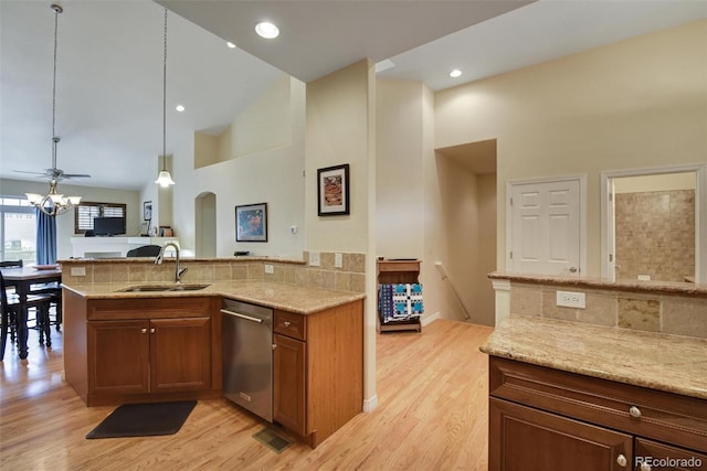 kitchen featuring dishwasher, a sink, and light stone countertops