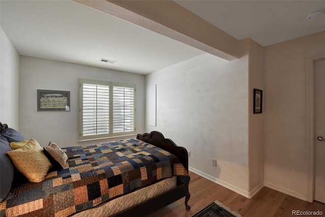 bedroom with visible vents, baseboards, and wood finished floors