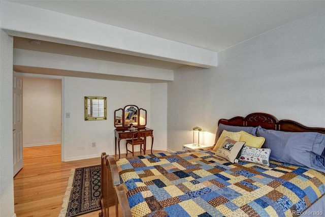 bedroom featuring light wood-type flooring, beamed ceiling, and baseboards