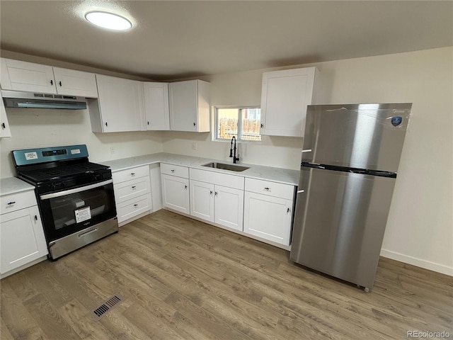 9036 Mandel St, Denver, CO 80260 - kitchen with stainless steel appliances, a sink, under cabinet range hood, light countertops, and white cabinetry