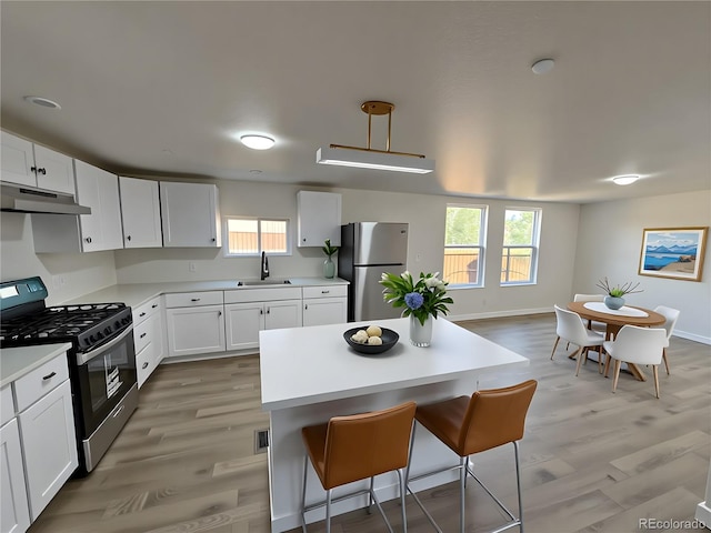 9036 Mandel St, Denver, CO 80260 - kitchen featuring range with gas stovetop, freestanding refrigerator, under cabinet range hood, a kitchen breakfast bar, and a sink