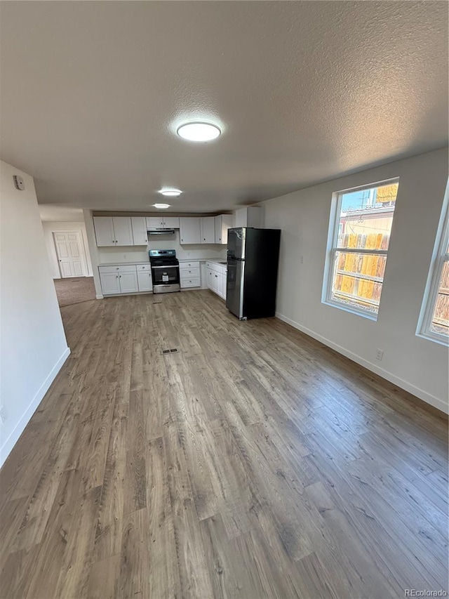 9036 Mandel St, Denver, CO 80260 - kitchen with stainless steel appliances, wood finished floors, white cabinetry, a textured ceiling, and baseboards
