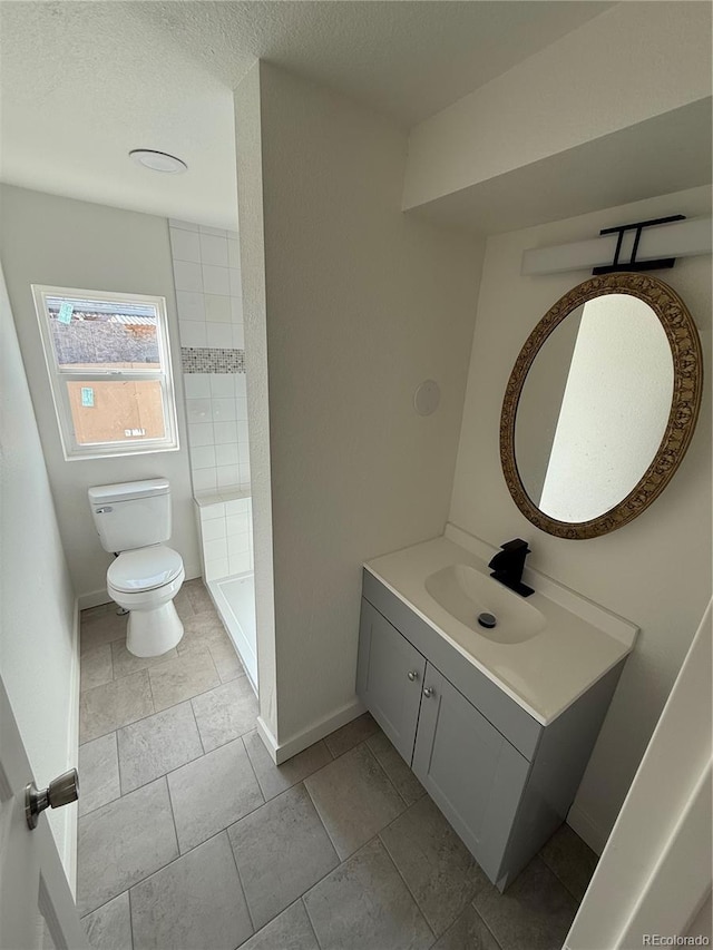 9036 Mandel St, Denver, CO 80260 - bathroom with toilet, vanity, baseboards, a tile shower, and a textured ceiling