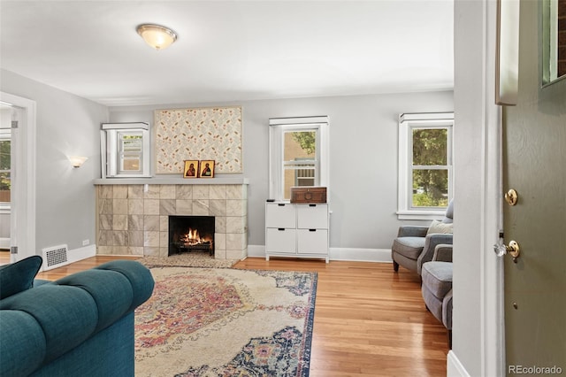 living room with light wood-type flooring, plenty of natural light, and a tile fireplace