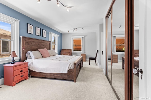 carpeted bedroom with a closet and track lighting