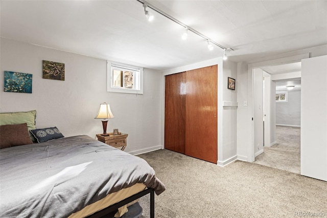 bedroom featuring light colored carpet, a closet, and track lighting