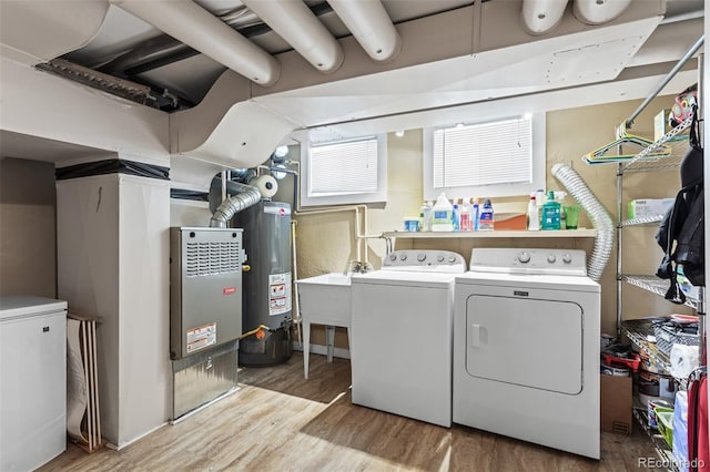 clothes washing area featuring wood-type flooring, sink, independent washer and dryer, and water heater