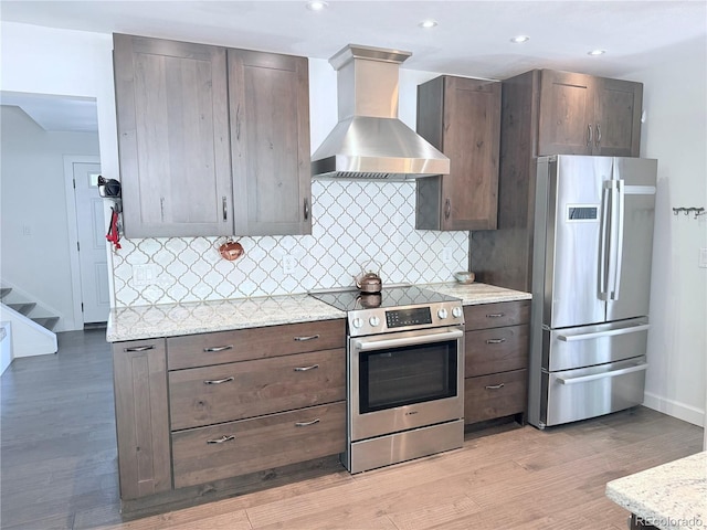 16796 E Union Ave, Aurora, CO 80015 - kitchen featuring stainless steel appliances, wall chimney exhaust hood, light wood finished floors, backsplash, and dark brown cabinets