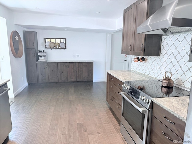 16796 E Union Ave, Aurora, CO 80015 - kitchen with wall chimney exhaust hood, appliances with stainless steel finishes, light wood-style floors, dark brown cabinetry, and tasteful backsplash