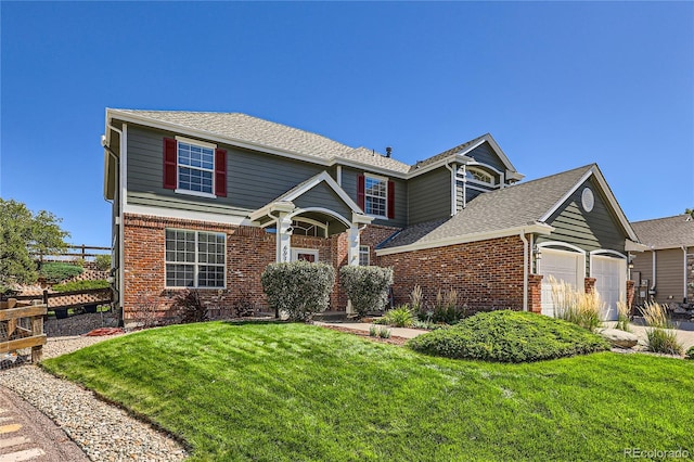 traditional-style house featuring brick siding, a shingled roof, an attached garage, a front yard, and fence