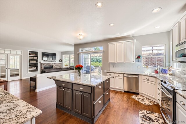 kitchen featuring a brick fireplace, white cabinetry, and appliances with stainless steel finishes