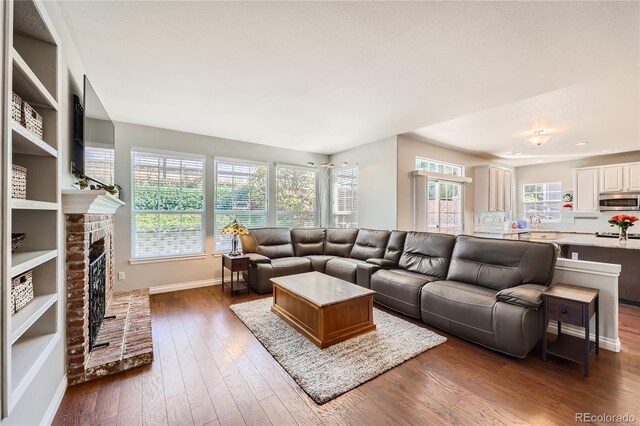 living room with dark wood-style floors, a fireplace, and baseboards