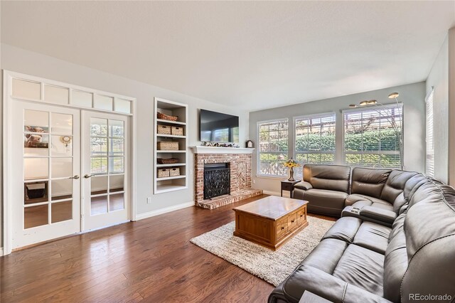 living room featuring baseboards, dark wood-style flooring, french doors, built in shelves, and a fireplace