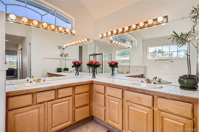 bathroom featuring lofted ceiling, a sink, and double vanity