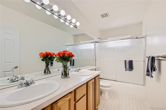 bathroom with shower / bath combination with glass door, visible vents, a sink, and double vanity