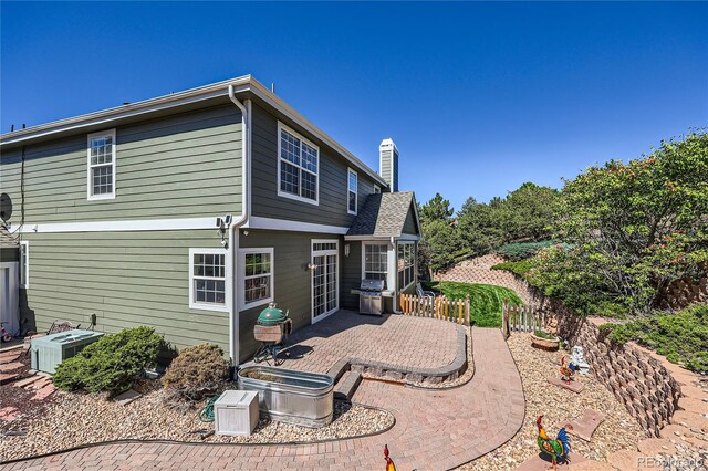 rear view of house featuring central AC, a patio, and a chimney