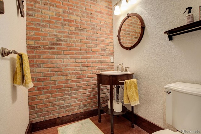 half bath with baseboards, wood finished floors, and toilet