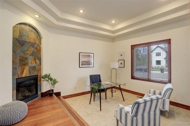 office area featuring a fireplace, baseboards, light colored carpet, recessed lighting, and a tray ceiling