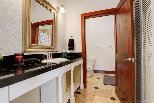 full bathroom with baseboards, tile patterned floors, vanity, and toilet
