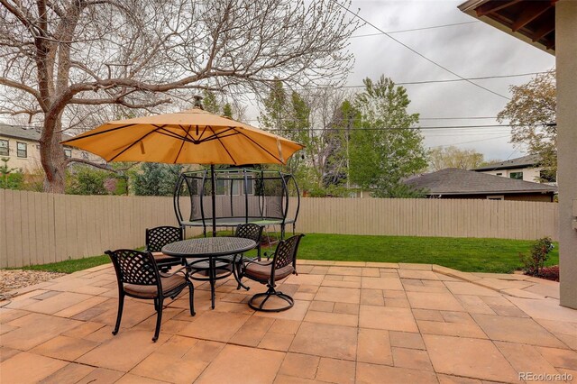 view of patio / terrace featuring outdoor dining area, a fenced backyard, and a trampoline