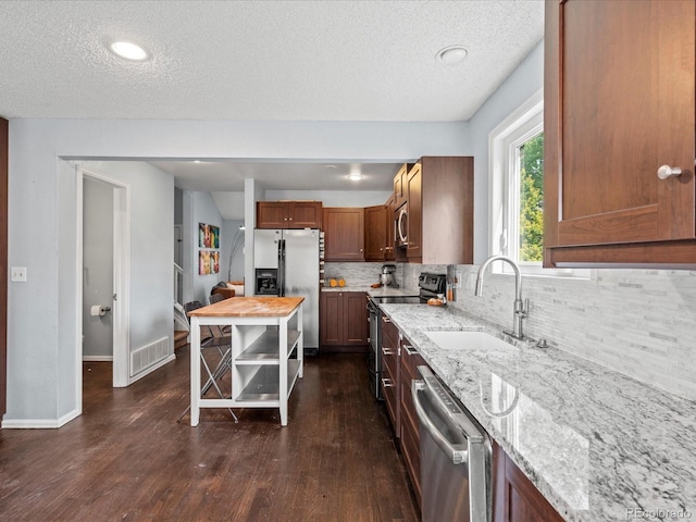 966 Cherry Blossom Ct, Highlands Ranch, CO 80126 - kitchen featuring stainless steel appliances, a textured ceiling, backsplash, dark wood-style floors, and light stone counters