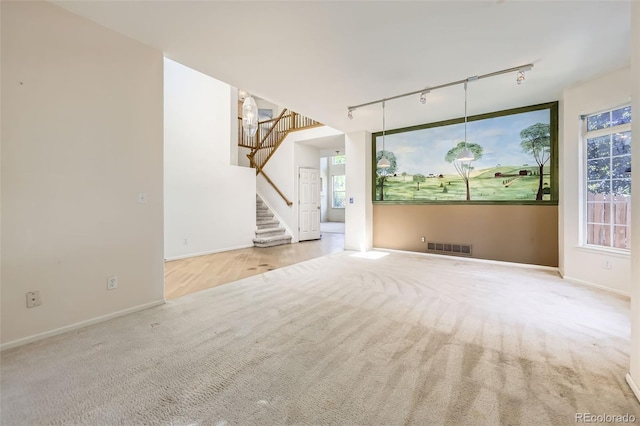 1730 Pear Ct, Brighton, CO 80601 - unfurnished living room featuring rail lighting, carpet flooring, and stairs