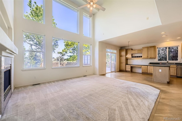 1730 Pear Ct, Brighton, CO 80601 - unfurnished living room with a high ceiling, a ceiling fan, a glass covered fireplace, and light wood-style floors