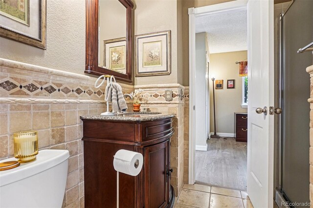775 Poppywood Dr, Highlands Ranch, CO 80126 - bathroom featuring tile walls, vanity, wainscoting, tile patterned floors, and a shower with door