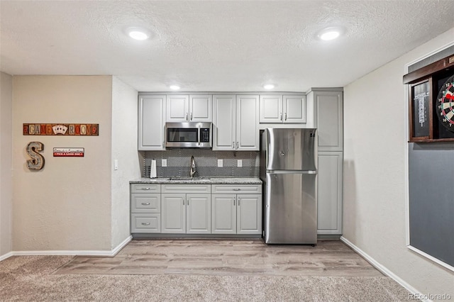 775 Poppywood Dr, Highlands Ranch, CO 80126 - kitchen featuring stainless steel appliances, a textured ceiling, tasteful backsplash, gray cabinetry, and light colored carpet
