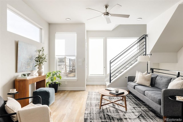 living area featuring stairway, baseboards, wood finished floors, and a ceiling fan