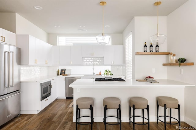 kitchen featuring stainless steel appliances, a kitchen bar, dark wood-style floors, and light countertops