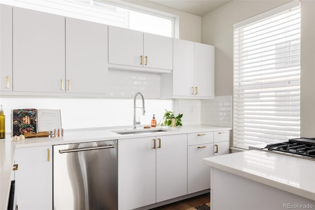 kitchen featuring backsplash, light countertops, appliances with stainless steel finishes, white cabinetry, and a sink