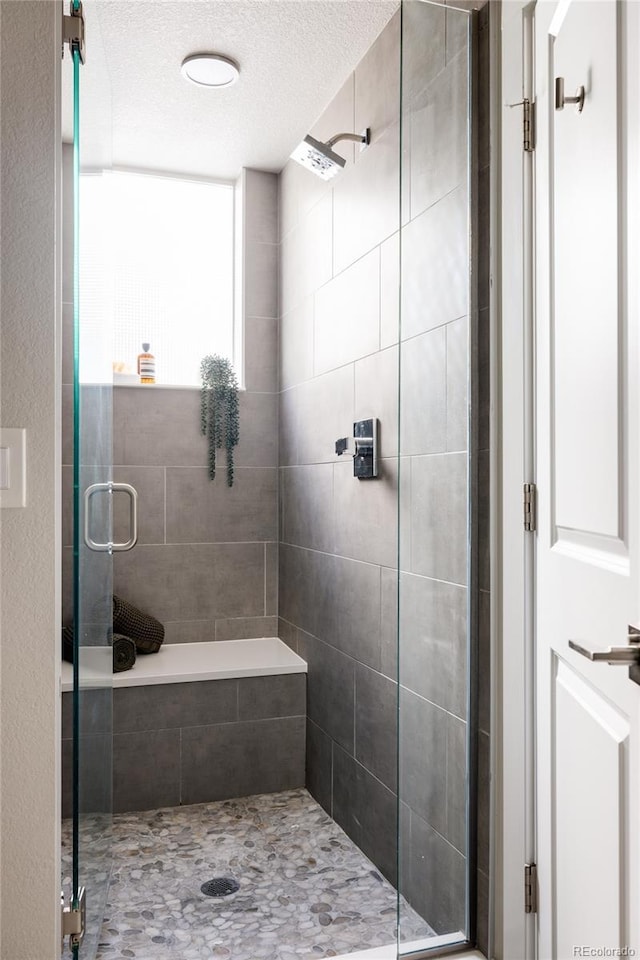 bathroom with a stall shower and a textured ceiling