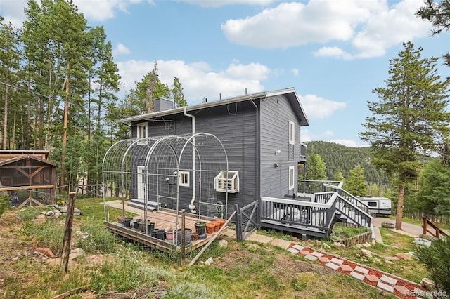 150 Cedar Rd, Evergreen, CO 80439 - back of property featuring a chimney, a wooden deck, and a wooded view