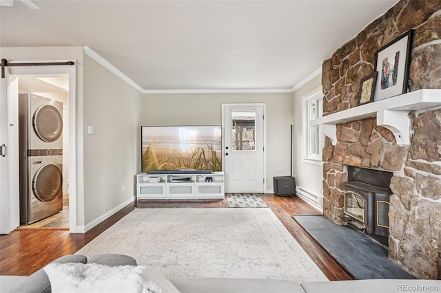 150 Cedar Rd, Evergreen, CO 80439 - living room featuring wood finished floors, stacked washing machine and dryer, a wood stove, baseboard heating, and crown molding