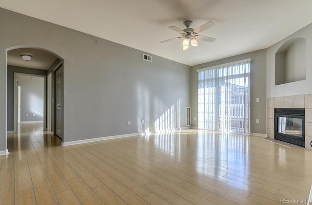 7440 S Blackhawk St Unit 12-204, Englewood, CO 80112 - unfurnished living room with arched walkways, a ceiling fan, baseboards, a fireplace, and light wood-style flooring