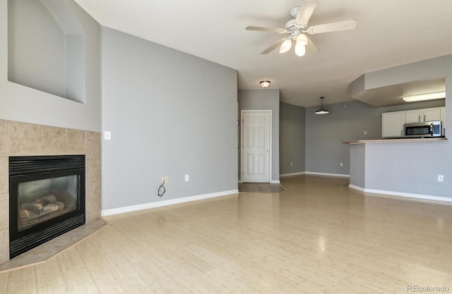 7440 S Blackhawk St Unit 12-204, Englewood, CO 80112 - unfurnished living room featuring light wood-type flooring, a tile fireplace, baseboards, and ceiling fan