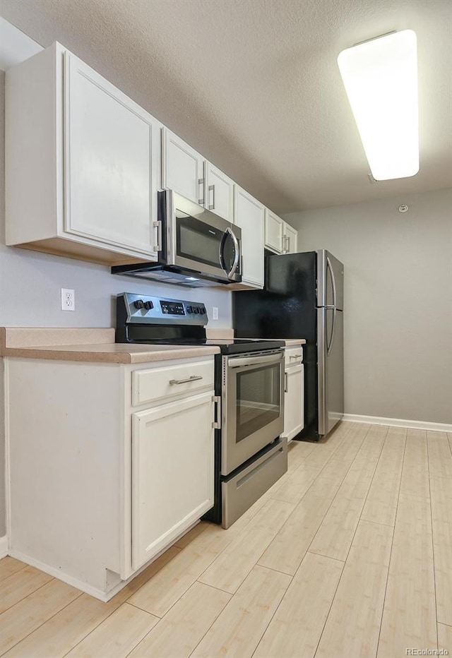 7440 S Blackhawk St Unit 12-204, Englewood, CO 80112 - kitchen with appliances with stainless steel finishes, light wood finished floors, white cabinets, light countertops, and a textured ceiling