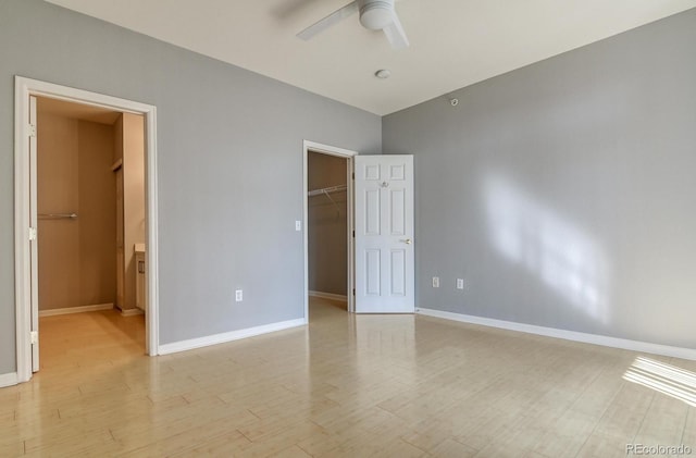 7440 S Blackhawk St Unit 12-204, Englewood, CO 80112 - unfurnished bedroom featuring a spacious closet, a closet, baseboards, light wood-style floors, and a ceiling fan