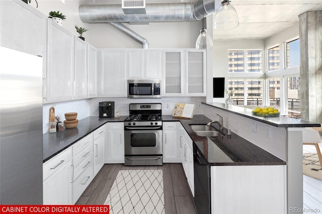 kitchen with kitchen peninsula, sink, dark hardwood / wood-style floors, white cabinetry, and appliances with stainless steel finishes