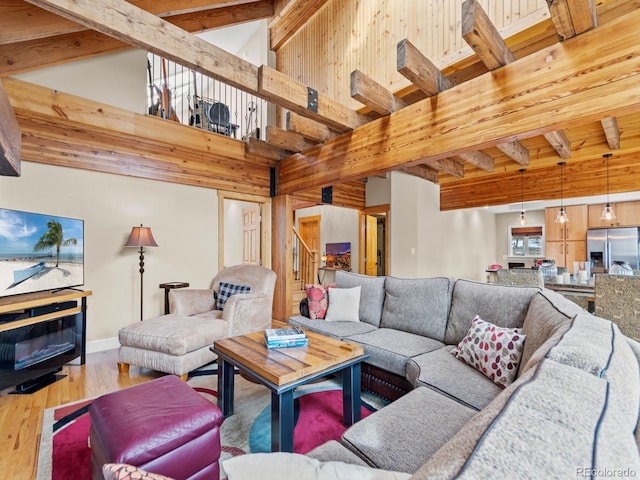 living room with wooden walls, beamed ceiling, wood-type flooring, and a high ceiling