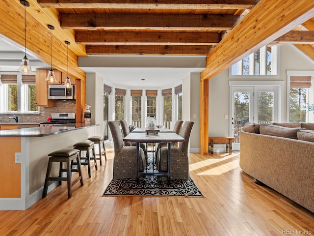 dining space with plenty of natural light, beamed ceiling, wooden ceiling, and light wood-type flooring