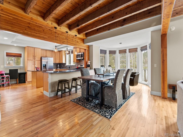 dining room featuring beamed ceiling, light wood-type flooring, and wood ceiling