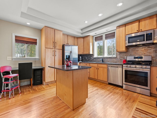 kitchen with a center island, sink, dark stone countertops, light wood-type flooring, and stainless steel appliances