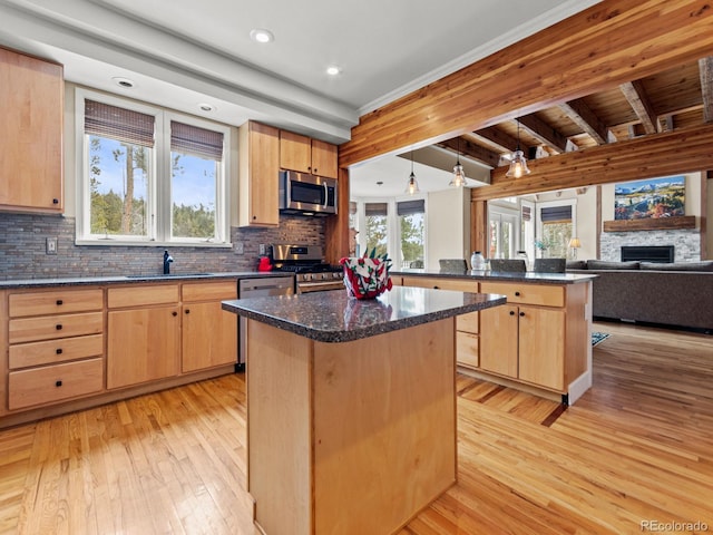 kitchen with a kitchen island, a stone fireplace, beam ceiling, and appliances with stainless steel finishes