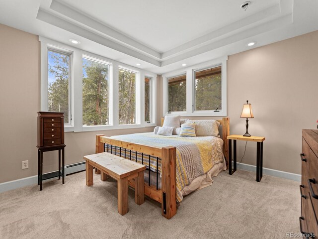 bedroom with a raised ceiling, light colored carpet, and baseboard heating