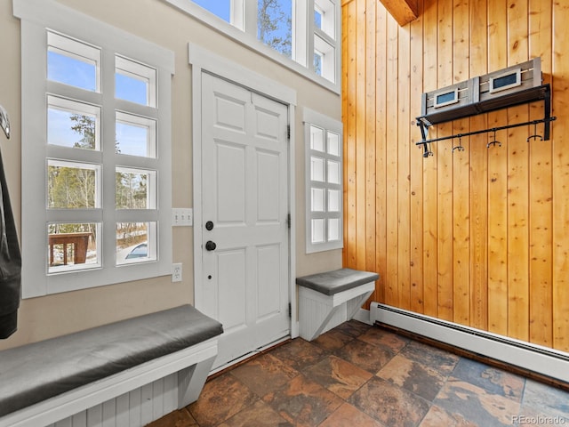 mudroom with wood walls, a towering ceiling, and a baseboard heating unit