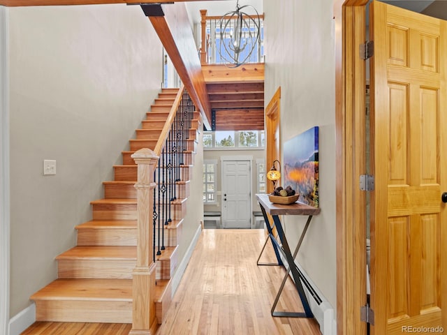 foyer entrance featuring an inviting chandelier, a towering ceiling, and light hardwood / wood-style flooring