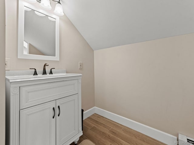 bathroom featuring hardwood / wood-style floors, vanity, and lofted ceiling