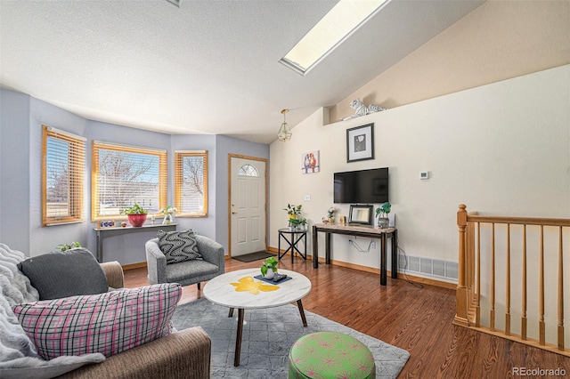 living room featuring visible vents, vaulted ceiling, baseboards, and wood finished floors